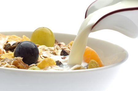 milk pouring in a bowl of muesli with grapes