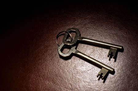 two keys on brown leather spot lightの写真素材