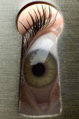 one eye looks through a keyhole close upの写真素材