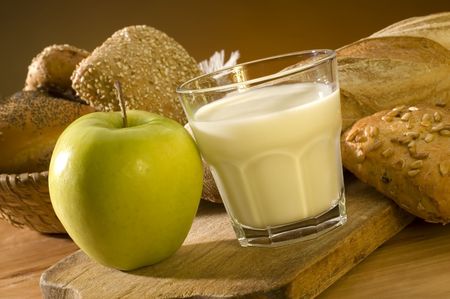 glass of milk apple and bread close upの写真素材