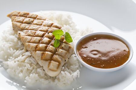 Grilled chicken steak with rice and hot sauceの写真素材