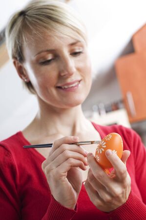 Young blond woman painting easter eggs close upの写真素材
