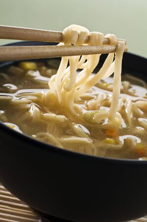 Chinese soup with noodles on chopsticks close up shoot の写真素材