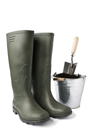 Garden boots and bucket with soil isolated on whiteの写真素材