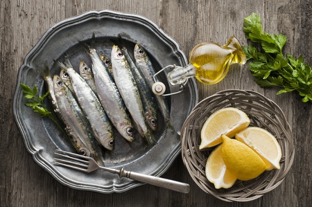 Fresh raw sardines with parsley and lemon on wooden backgroundの写真素材