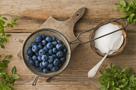 Fresh blueberries in small strainer on wooden backgroundの写真素材