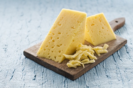 Hunch of cheese on blue background close up