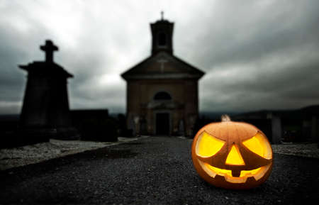 A glowing Jack O Lantern in a dark mist graveyard on Halloweenの写真素材