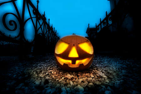A glowing Jack O Lantern in a dark mist graveyard on Halloweenの写真素材