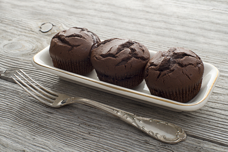 Muffins with chocolate on white plate on wooden backgroundの写真素材