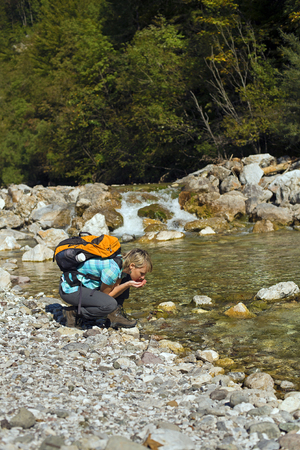 Hiker with backpack drinking water with handsの写真素材