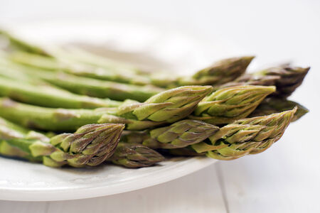 Fresh green asparagus on white plate close upの写真素材