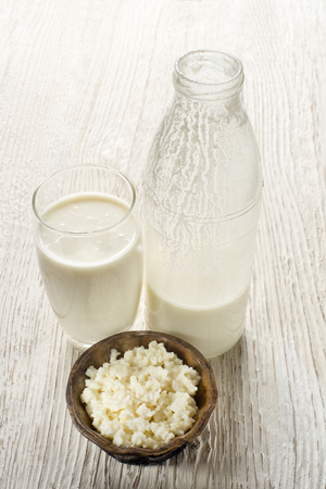 Milk kefir and grains in glass on wooden tableの写真素材