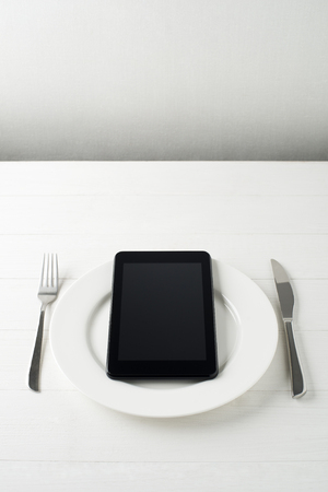 Tablet computer on a plate with fork and knife conceptual shootの写真素材