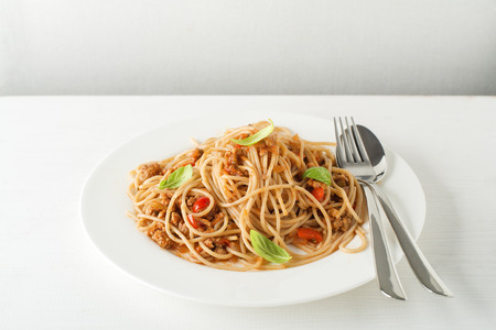 Spaghetti with Bolognese sauce and basil served on a white plateの写真素材