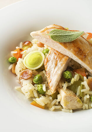 Risotto with vegetable and chicken served on white plate close upの写真素材