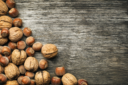 Whole walnuts and hazelnuts on a wooden backgroundの写真素材
