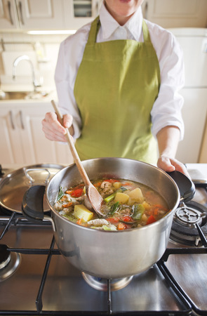 woman cooking vegetable soup in the potの写真素材