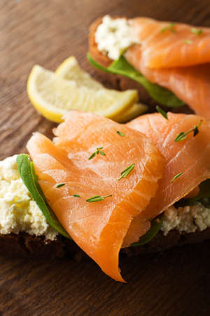 Slice of smoked salmon with bread on wooden backgroundの写真素材