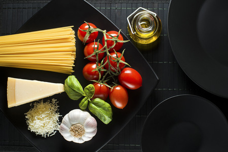 Spaghetti and tomatoes with parmesan cheese on black tableの写真素材