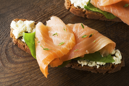 Slice of smoked salmon with bread on wooden backgroundの写真素材
