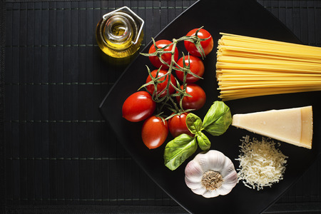 Spaghetti and tomatoes with parmesan cheese on black tableの写真素材