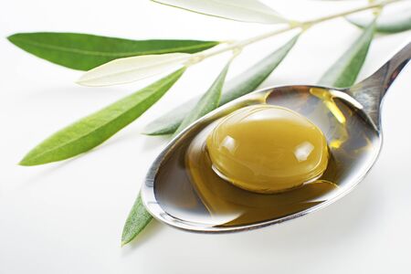 Olive fruit in spoon with oil background close upの写真素材