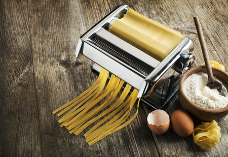 Fresh pasta making in machine on wooden backgroundの写真素材