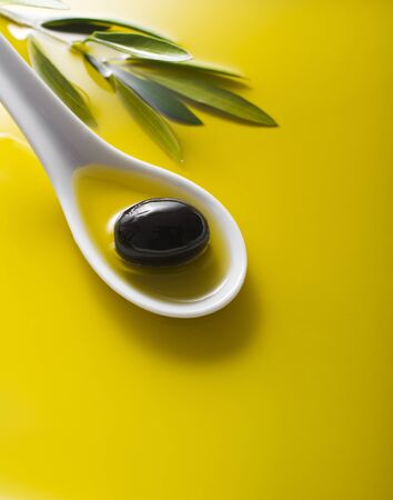 Olive fruit in spoon with oil background close upの写真素材