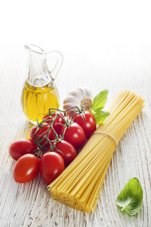 Spaghetti and tomatoes with oil on a vintage wooden tableの写真素材