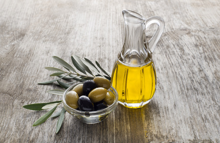 Olive oil and olive branch on the wooden tableの写真素材