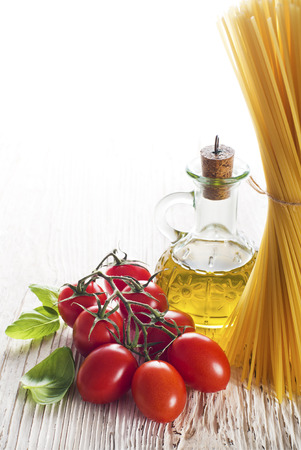 Spaghetti and tomatoes with basil on a vintage wooden tableの写真素材
