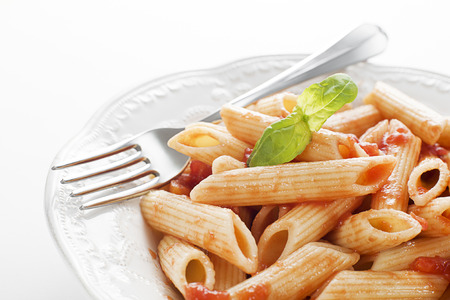 Plate of penne pasta with tomato sauce and basilの写真素材