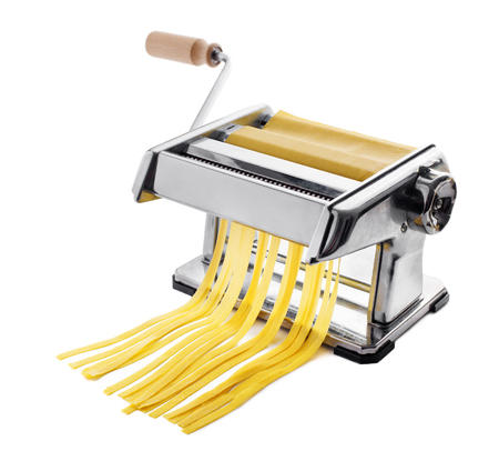 Fresh pasta cutting in machine isolated on white. Fettuccini homemade.の写真素材