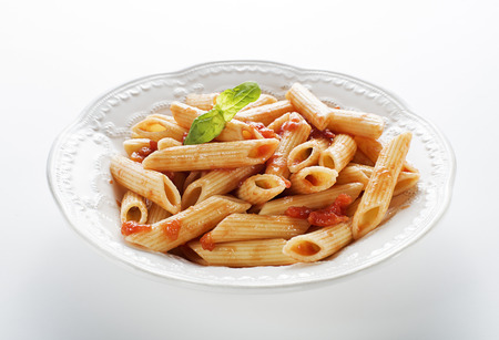 Plate of penne pasta with tomato sauce on white backgroundの写真素材