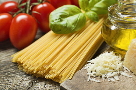 Spaghetti and tomatoes with parmesan cheese on a vintage wooden table close upの写真素材