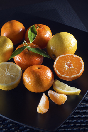 Fresh citrus fruits with green leaves on black backgroundの写真素材