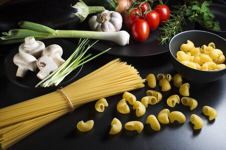 Pasta collection with fresh ingredients on a black background.の写真素材
