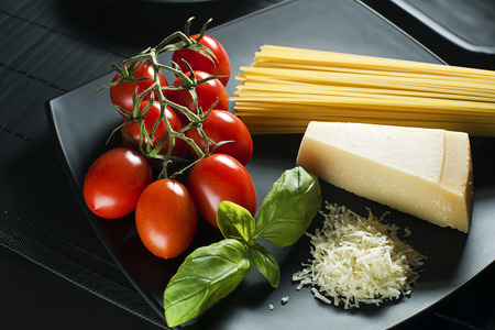 Spaghetti and tomatoes with parmesan cheese on a black table.の写真素材