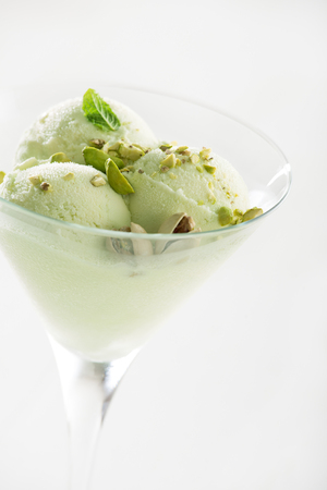 A scoop of pistachio ice cream with pistachios in glass close up.の写真素材