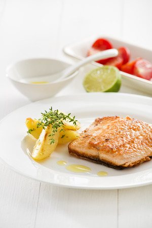 Grilled Salmon with roasted potatoes served on a plate.の写真素材