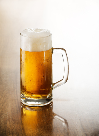Glass of cold beer on a wooden table.の写真素材