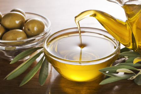 Bottle pouring virgin olive oil in a bowl close up.の写真素材