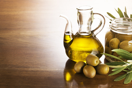 Olive oil and olives on a wooden table.の写真素材