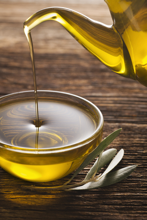 Bottle pouring virgin olive oil in a bowl close up.の写真素材