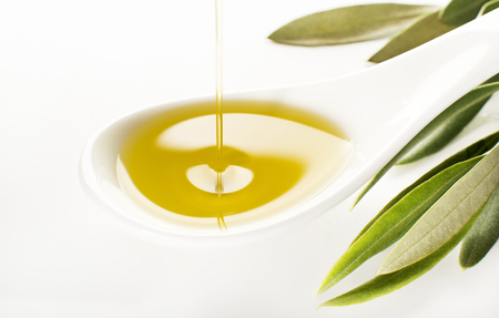 Virgin olive oil pouring on white spoon.の写真素材