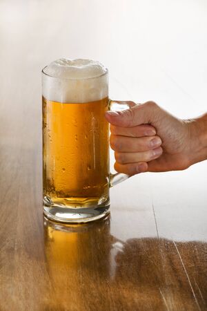 Bartender holding a freshly tapped glass of beer in his hand.の写真素材