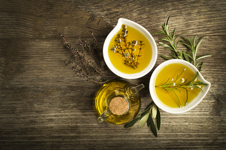 Olive oil with fresh herbs on wooden background.の写真素材