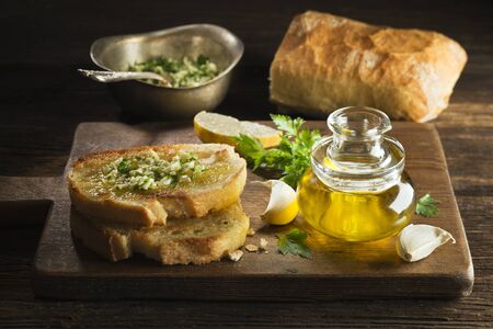 Toasted bread with garlic, herbs and olive oil on wooden background.の写真素材
