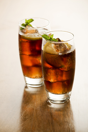 Two Glasses of fresh cola or soda drink with ice cubes and lemon.の写真素材